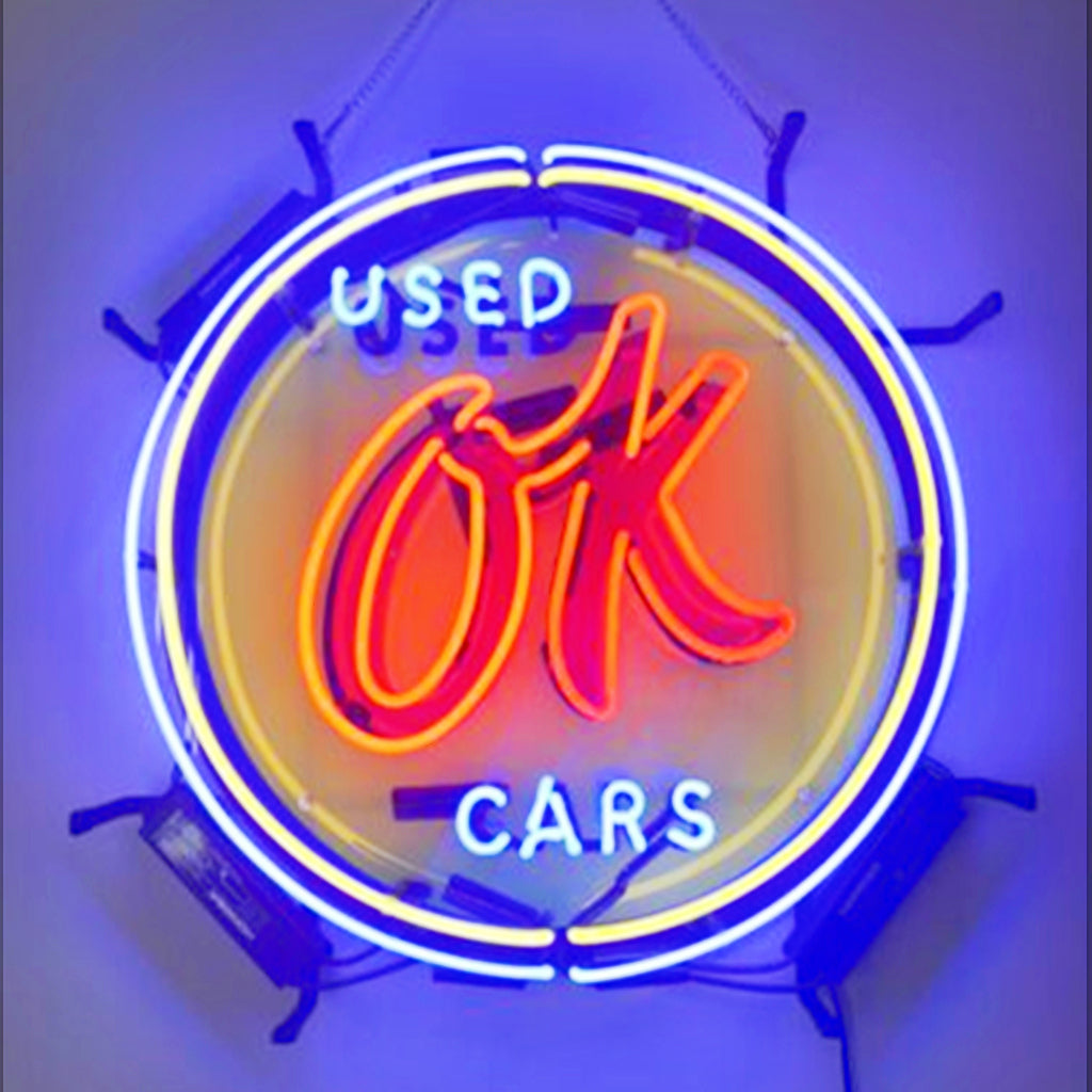 Used OK Cars neon sign glowing in a metal grid backing hung on a wall