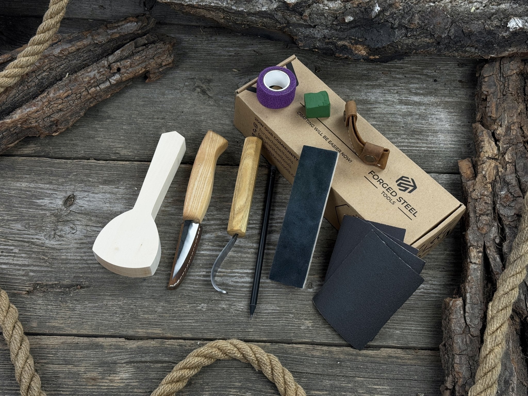 Beginner wood carving kit with sloyd knife, hook knife, wooden blank, sandpaper, sharpening board, pencil, and finger wrap