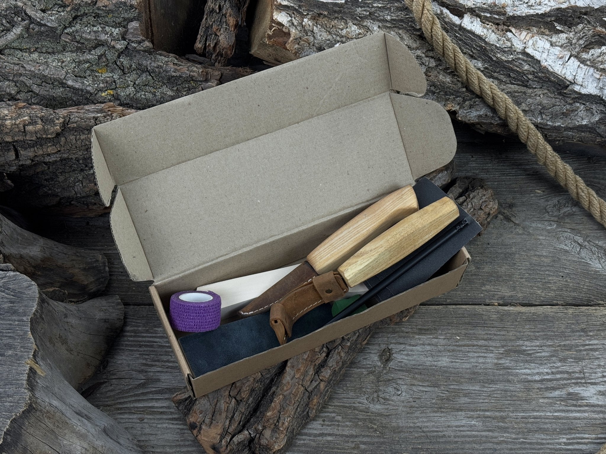 Beginner wood carving kit with sloyd knife, hook knife, wooden blank, sandpaper, sharpening board, pencil, and finger wrap