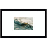 Framed wall art print featuring a surfer riding a cresting wave with morning light illuminating the spray against a pale sea background.