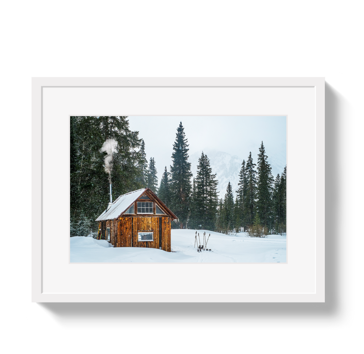Rustic wooden hut with smoke rising from its chimney, surrounded by snow and tall evergreen trees on a foggy winter day