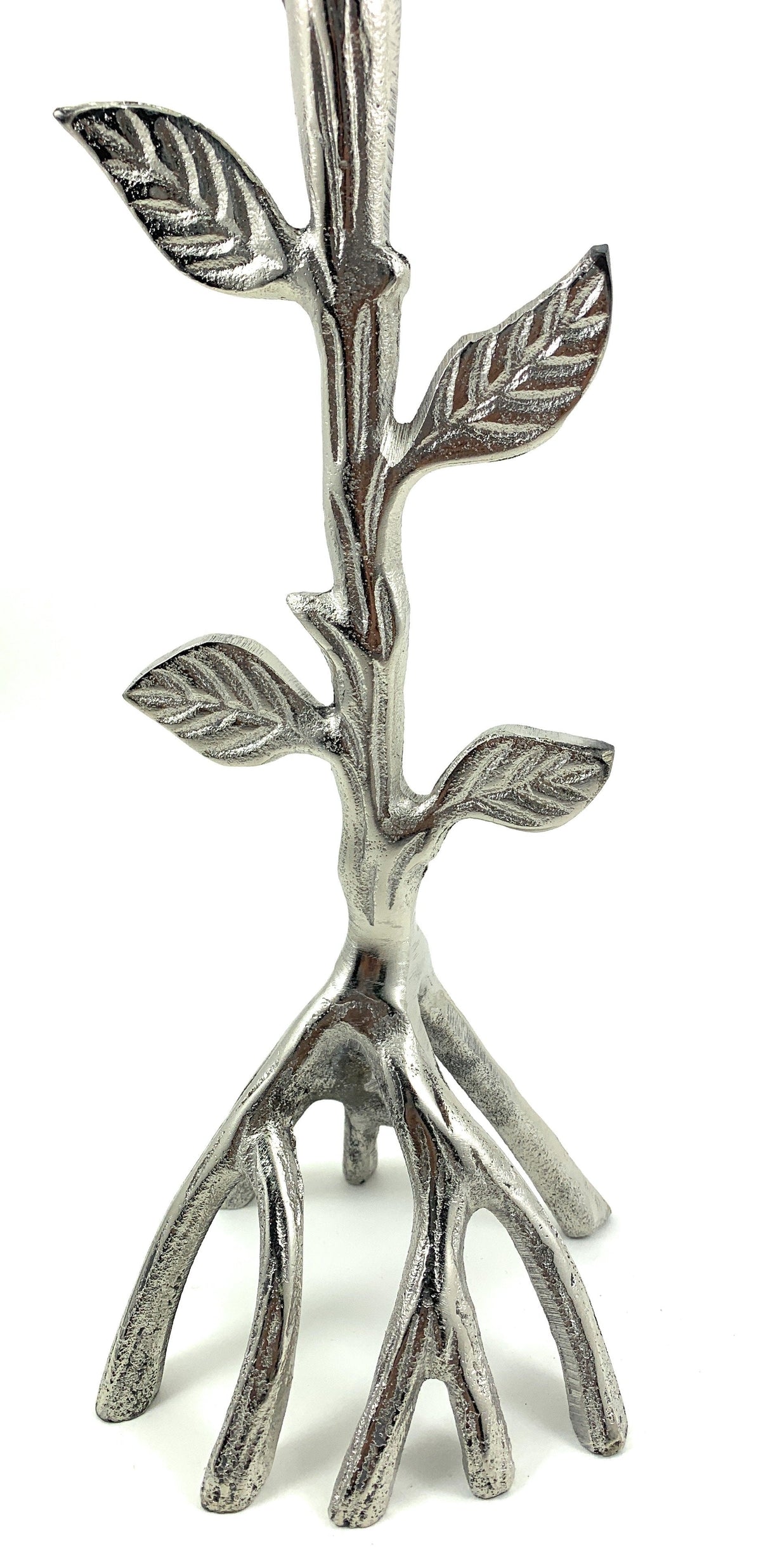 Silver metal candle holder shaped like a tree branch with detailed textured leaves and roots forming the base on a white background.