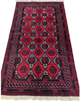 Rectangular hand-knotted Afghan Baluch wool rug with repeating red and black geometric medallions and multiple patterned borders, finished with white fringes on short ends.