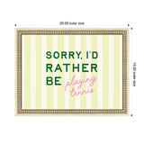 Rectangular framed wall art with pale yellow and cream vertical stripes and text reading "SORRY, I'D RATHER BE playing tennis" in green and pink letters.