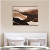 Abstract landscape painting with layered soft brown, beige, and black brushstrokes in a dark wood frame above a white upholstered bed with neutral-toned pillows.