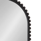 Close-up of an arched wall mirror with a black frame adorned by evenly spaced rounded beads along the outer edge, against a plain light background.