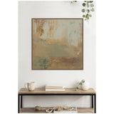 Abstract landscape painting in muted sage green, beige, and brown hues framed in wood, hanging above a wooden console with a white mug and decorative vase with greenery.
