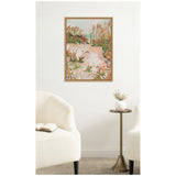 Abstract framed painting of a sandy path bordered by green and brown grasses with soft peach and blue sky hues, hanging on a white wall above a brass side table.