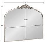 Arch-shaped mirror with a 36-inch width and 28.5-inch height, featuring a decorative ornamental crest at the top center in a muted silver finish.
