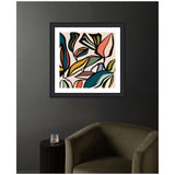 Framed abstract plant art print with bold curved shapes in teal, pink, yellow, and black lines on a pale background, hung on a dark gray wall above an olive green chair.