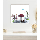 Framed canvas art of three whimsical mushrooms with maroon and blue caps, surrounded by green leaves, pinecones, and a small blue butterfly on white background.