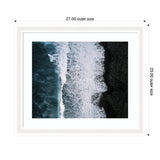 Aerial view of ocean waves crashing onto a black volcanic sand beach with white foam patterns, framed in white with dimensions labeled.
