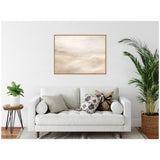 Minimalist living room with white sofa adorned with patterned throw pillows, framed beige and white abstract painting above, and green plants on each side.