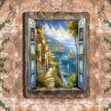 Open blue shutters revealing a painted seaside cliffside village with stone path, sailboats on blue water, distant mountains, and light clouds.