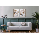 Modern living room with light gray upholstered sofa featuring a round pleated cushion, set against green wainscoting and two beige abstract canvas prints above.
