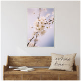Framed canvas print of delicate white blossoms on branches against a soft blue and pink gradient background, hung above a rustic wooden bench with a 'welcome home' pillow.