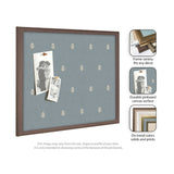 Square pinboard with blue canvas featuring a repeating pattern of small cream botanical motifs and a dark wood frame, displaying two pinned vintage black-and-white photos.