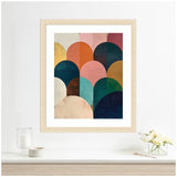 Minimalist abstract art featuring overlapping semi-circles in jewel tones of teal, coral, mustard, and navy, framed in light wood on a white wall above a shelf.