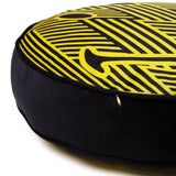 Round cushion with a bold yellow and black zig-zag pattern on top and a plain black fabric side, featuring a small gold zipper pull.