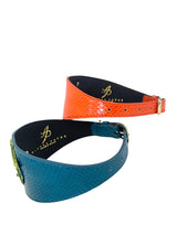 Two alligator texture leather collars, one bright orange with gold buckle, the other teal blue with a green alligator-shaped embellishment.