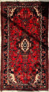 Hand-knotted Persian Hamadan rug with red field, cream-colored central medallion, and intricate floral motifs in black and blue borders.