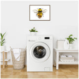 Framed canvas print of a detailed yellow and black bumblebee with translucent wings hanging above a white front-loading washing machine in a minimalist laundry room.