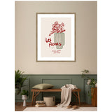 Framed wall art featuring a minimalist red floral line drawing in a vertically striped vase with 'Les fleurs' text, displayed above a wooden bench with soft cushions and plants.