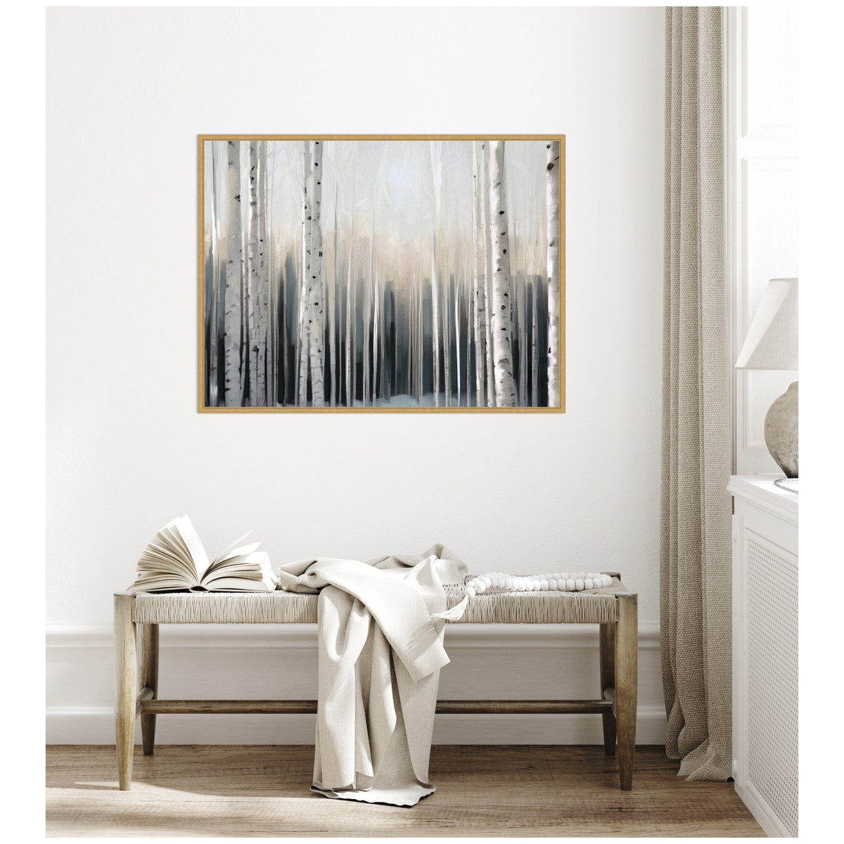 Framed canvas painting of a misty birch forest in muted grays and soft whites hanging above a wooden bench draped with neutral-toned textiles in a minimalist room.
