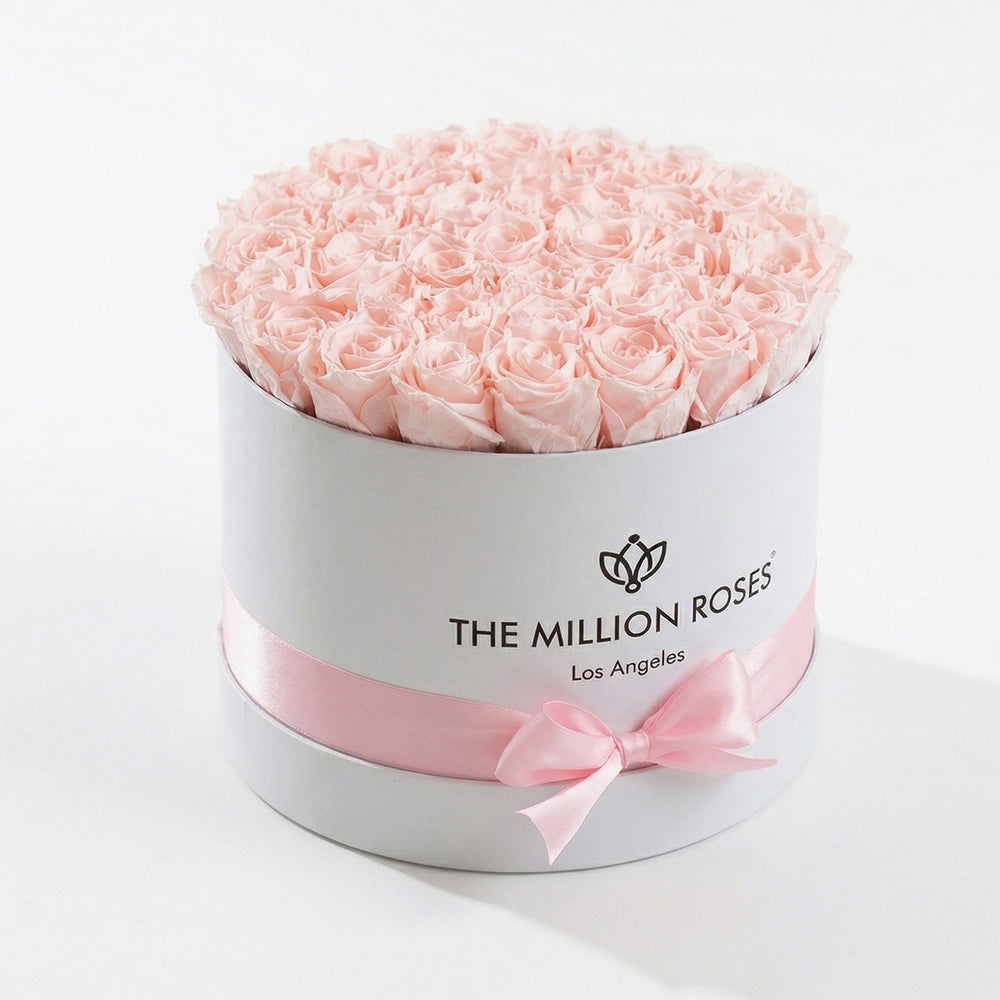 Supreme White Box containing 26-28 light pink preserved roses arranged neatly