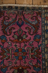 Close-up of a vintage Borchalou rug corner featuring intricate floral and geometric patterns in deep pink, blue, and rust tones with a cream fringe and muted border.