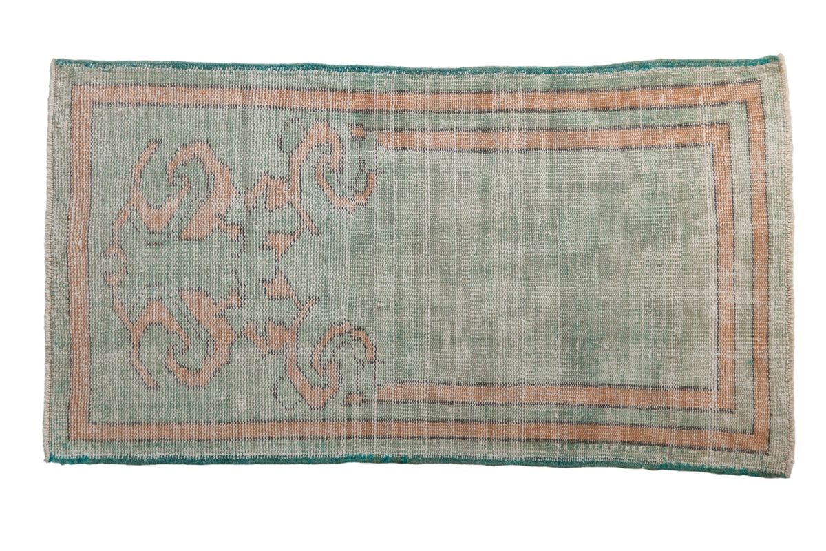 Vintage distressed Oushak rug featuring scrolling leaf and vine prayer motif in pale mint green, dusty gold, and oxidized silver