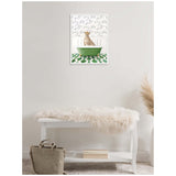 Framed canvas of a cheetah sitting inside a green bathtub with white and green patterned floor and floral wallpaper, displayed above a white bench with a beige fur throw.
