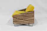 Loveseat with smooth mocha and natural zebra-striped wooden arms, angled sides, and bright yellow cushioned seat and back, resting on minimalist metal legs against a plain background.