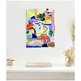 Colorful abstract painting with bold red, blue, green, and yellow shapes, organic curves, and geometric lines, framed and hung on a white wall above a minimalist table.