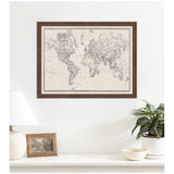 Framed vintage-style black and white fabric map of the world with detailed continents on a linen-textured background, hanging above a white shelf with decor.