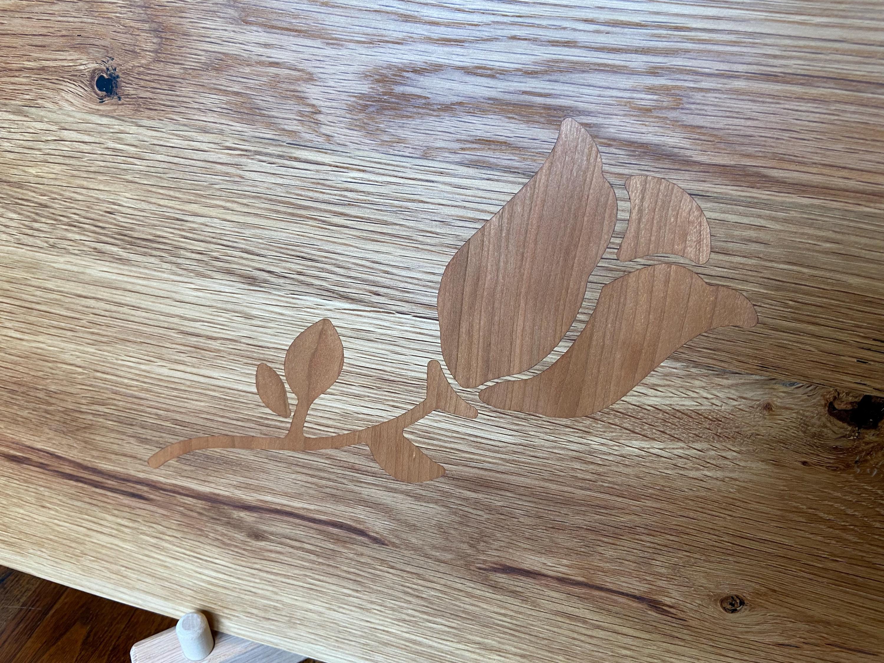 White Oak charcuterie board with subtle Cherry rose and stem inlay, handcrafted by Fitzgerald Custom Woodcraft