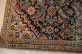 Close-up of a square pillow with an intricate vintage rug fragment pattern in dark blue, rust, and beige tones, featuring floral and geometric motifs.