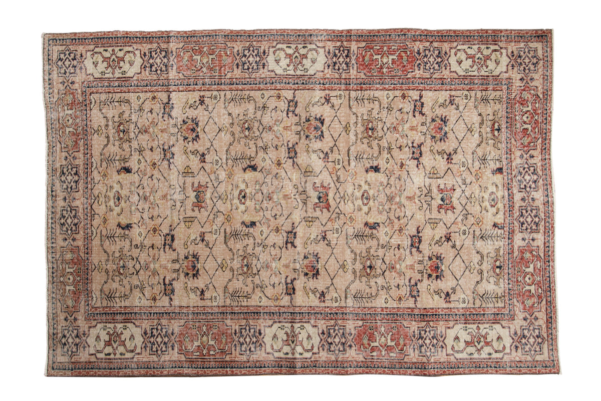 5.5x8 Vintage Distressed Sparta Carpet spread flat showcasing lattice vine pattern and partial Samovar Turtle border in beige, dusty cherry red, navy blue, and ivory