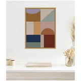 Framed canvas featuring abstract geometric shapes in muted earth tones like brown, navy, and lavender arranged in a minimalist grid on a white wall above a light wood surface.