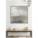 Abstract wall art with soft grey, beige, and light blue tones framed in warm wood, hung above a wooden console table with neutral decor accents.