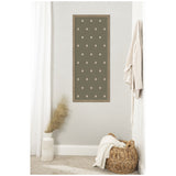Tall rectangular wall art with green background and scattered white botanical dots, hung on a light gray wall in a corner with neutral decor and woven basket.