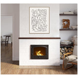 White brick fireplace with a black metal insert burning firewood, topped by abstract black line art on white canvas in light wood frame, beside wood shelves and armchair