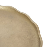 Close-up of a gold-toned decorative tray with an irregular, wavy rim and a subtly textured surface, shown at an angle on a white background.