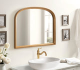 Arch-shaped wall mirror with a warm wood frame above a white oval vessel sink with a brass faucet, surrounded by neutral-toned decor and small framed photos.