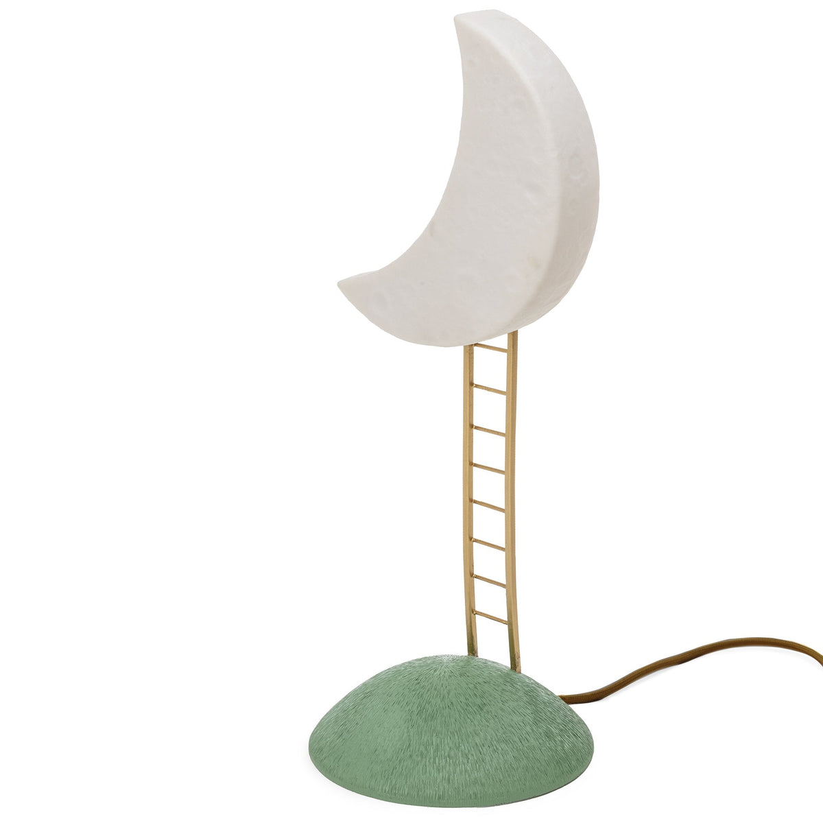 Table lamp shaped like a white crescent moon elevated by a thin vertical brass ladder from a textured green dome base, with an electric cord extending beside the base.