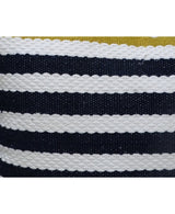 Close-up of a textured outdoor pillow with alternating thick black and white horizontal stripes and a glimpse of olive green fabric at the top edge.