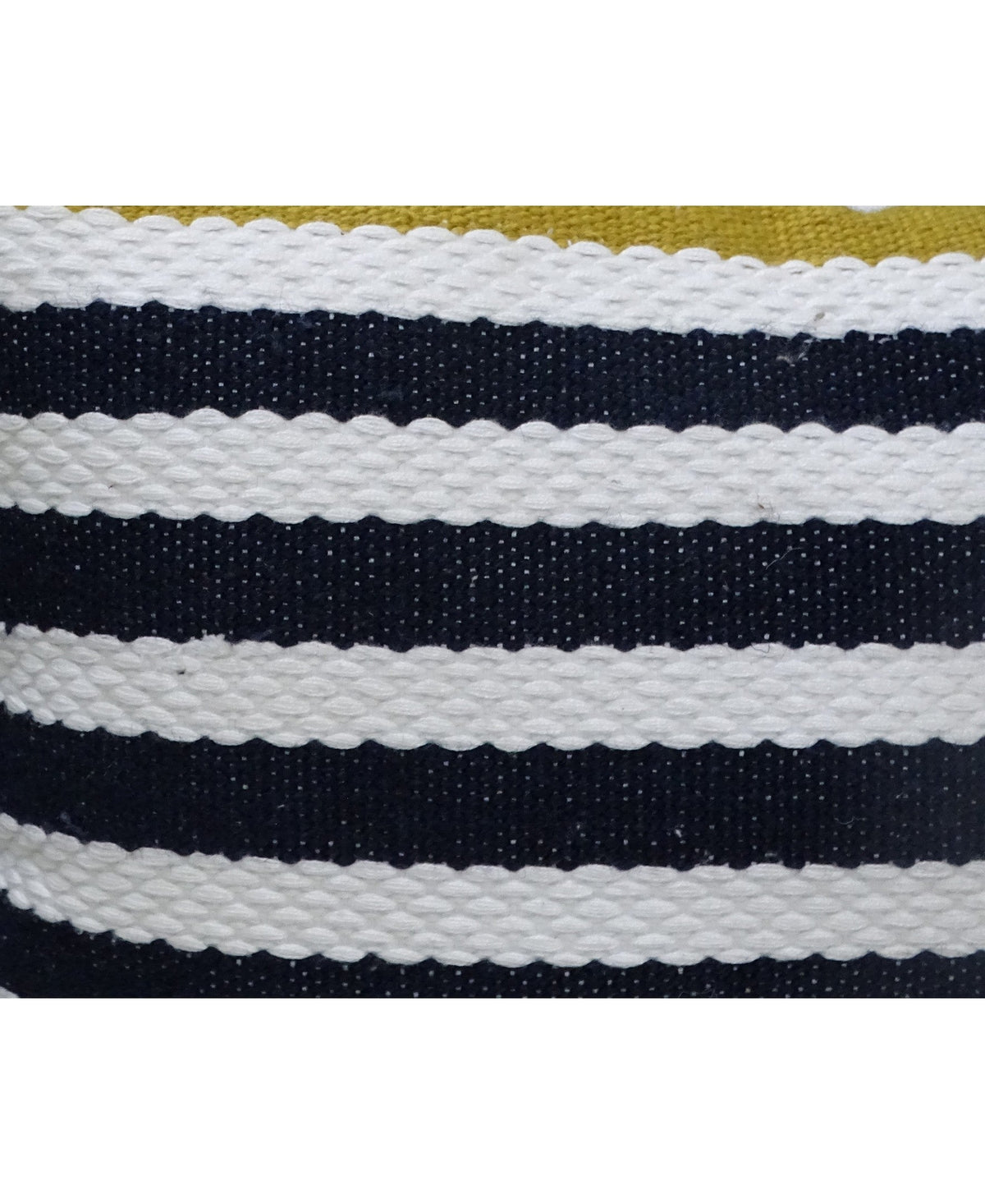 Close-up of a textured outdoor pillow with alternating thick black and white horizontal stripes and a glimpse of olive green fabric at the top edge.