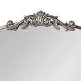Ornate silver-toned carved floral and scrollwork crest atop an arched mirror frame with smooth edges.
