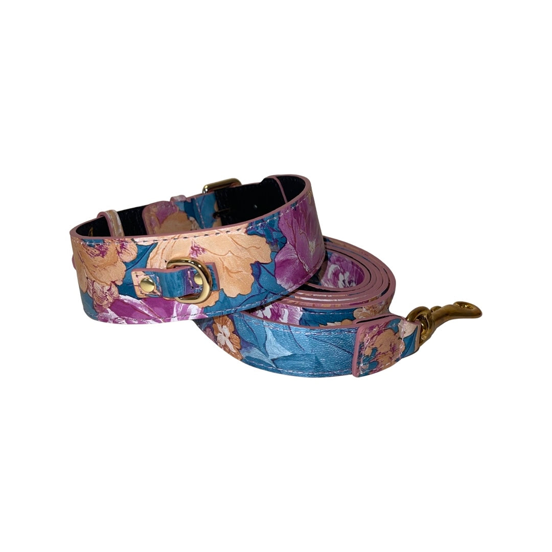 Dog collar and leash set with a floral print in shades of purple, blue, and beige, featuring gold-tone hardware and a leather texture.