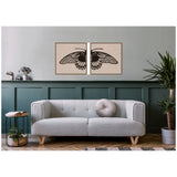Two framed canvas art pieces forming a black butterfly wing spread on beige background above a light gray sofa with a round pillow, surrounded by green paneled wall and plants.